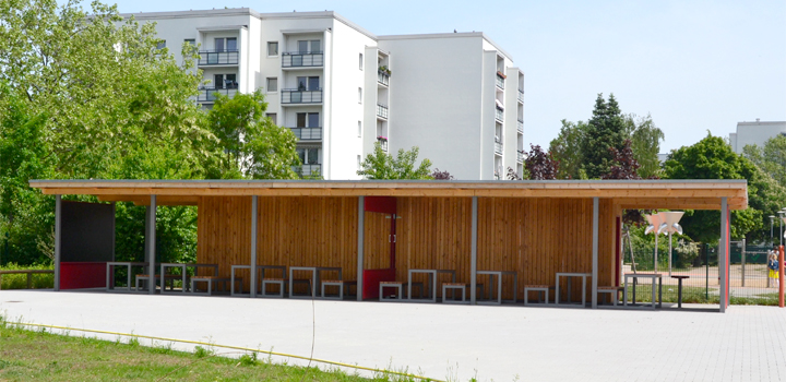 Aufenthaltsbereich im Freien mit Holzwänden, Metallrahmen, Tischen und Stühlen, von FreiraumObjekte Ney GmbH.